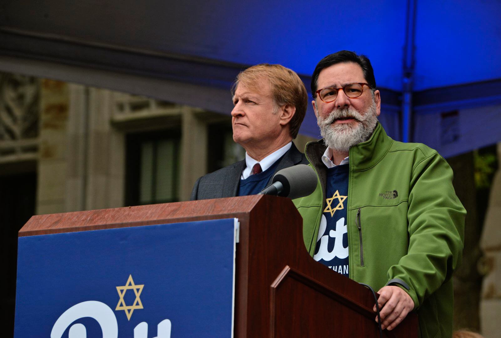 Pittsburgh Mayor Bill Peduto speaks as Allegheny County Executive Rich Fitzgerald looks on during a tribute for Tree of Life victims outside the Cathedral of Learning on the University of Pittsburgh campus Monday, Nov. 5, 2018.