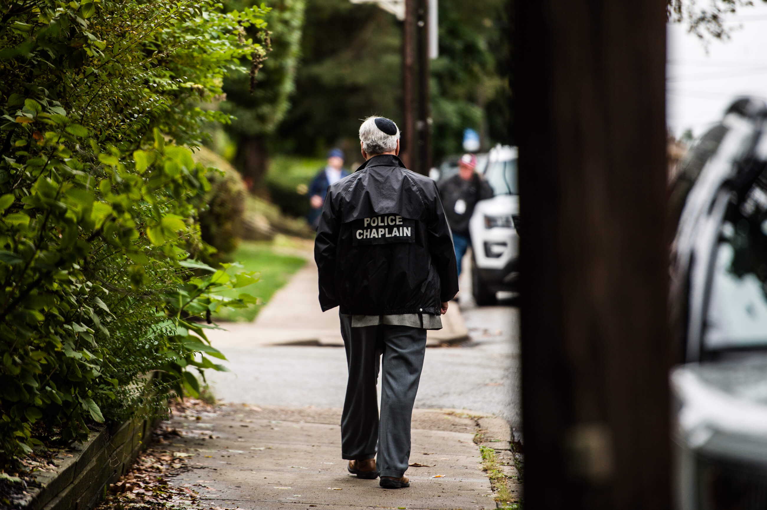 A police chaplain walks the sidewalk near the Tree of Life synagogue hours after the shooting last year.