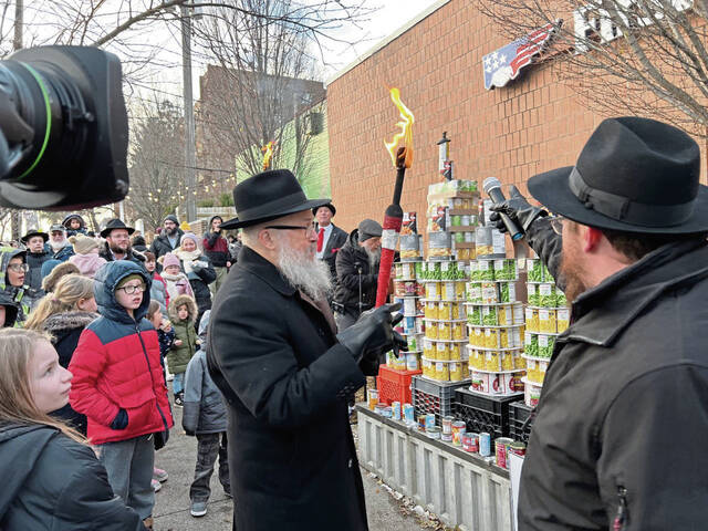 5733522_web1_Rabbi-Yisroel-Rosenfeld-left-lights-the-Menorah