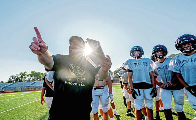 The early morning sun rises as Kiski Area coach Colyn Haugh works with his varsity squad during the first day of football practice Monday, Aug. 11, 2025.