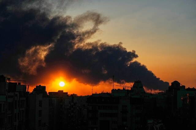 The sun sets behind a plume of smoke rising after a U.S.–Israeli military strike in Tehran, Iran. (AP)