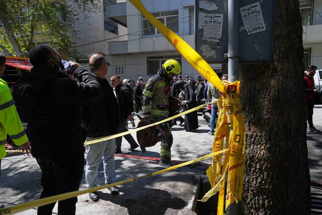 A first responder leaves the site of a strike Tuesday that, according to a security official at the scene, destroyed half of the Khorasaniha Synagogue and nearby residential buildings in Tehran, Iran. (AP)