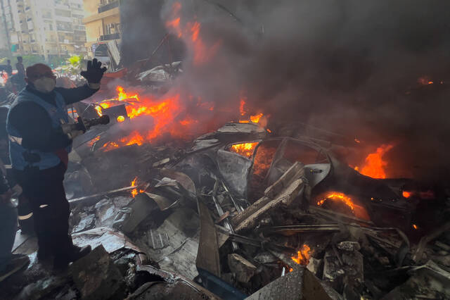 A rescue worker extinguishes burning cars at the site of an Israeli airstrike in central Beirut, Lebanon. (AP)